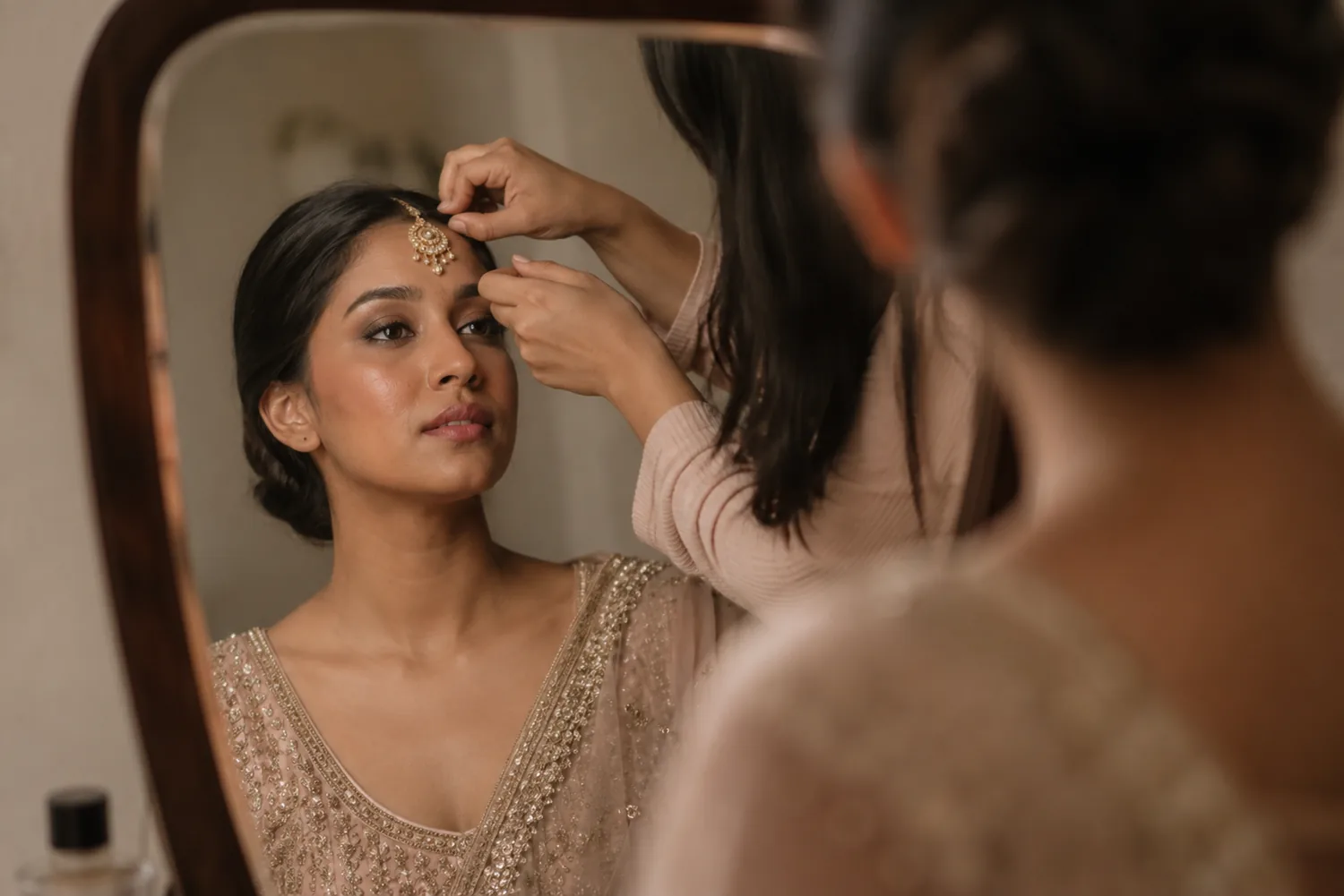 A maang tikka being adjusted, seen in the mirror